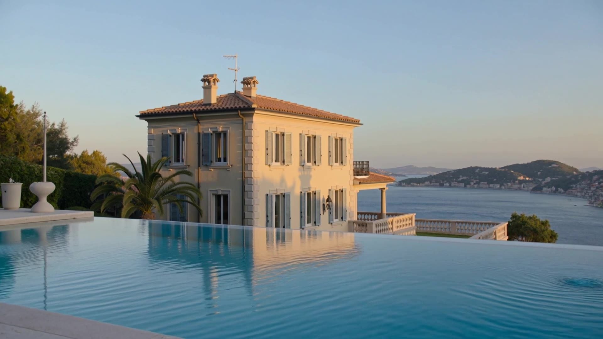 A stone villa above an infinity pool and the sea in the evening sun